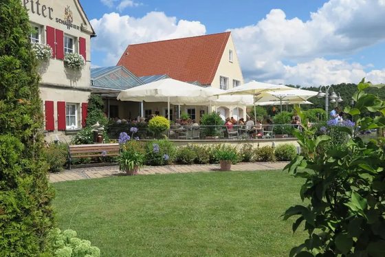Terrasse und Rasenfl&auml;che des Restaurants &bdquo;Zum Hochreiter&ldquo; mit Sonnenschirmen